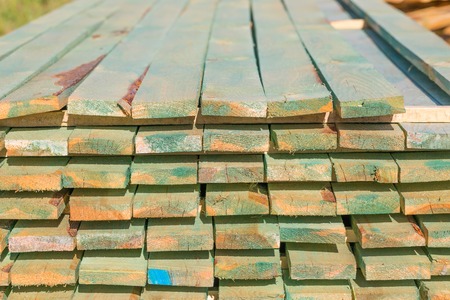 Boards from sawmill for house roof construction. Wooden planks lying in the yard.