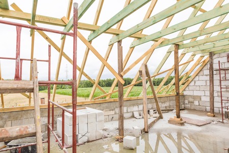 Unfinished house in countryside. Part of house with wooden construction of roof. Building a house in...
