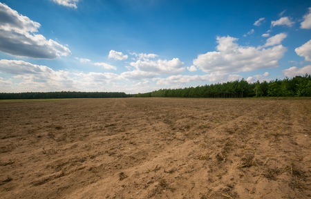 Beautiful plowed field under cloudy sky. Autumnal landscape of polish countryside.