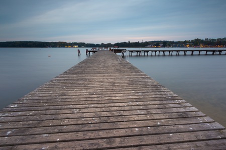 Landscape with wooden jetty on city beach of Olsztyn in Poland. Long exposure landscape with architecture elements.の写真素材