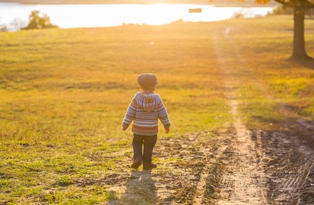 Little boy walking and playing in outdoor near autumnal forest. Caucasian child photographed from behind.の写真素材
