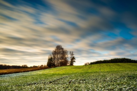 Early winter or late autumnal landscape of long exposure field at good weather. Fields with little snow.の写真素材