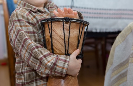Small child playing on drum. Little caucasian boy and drum. Hands close upの写真素材