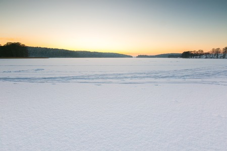 Sunset sky over frozen and snowy lake. Beautiful winter landscape photographed in Poland.の写真素材