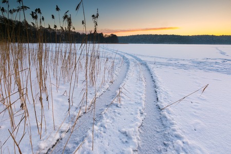 Sunset sky over frozen and snowy lake. Beautiful winter landscape photographed in Poland.の写真素材