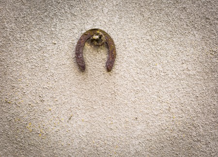 Old destroyed concrete wall background with hanged old horseshoe. Texture usefull as backdropの写真素材