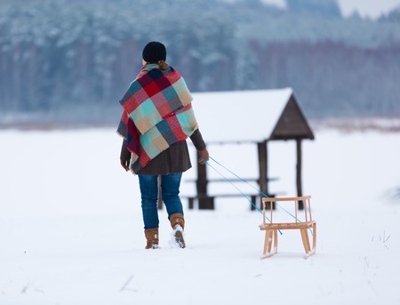 Winter landscape with woman pulling sled, photo from behind.の写真素材