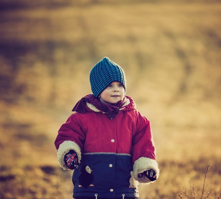 Young happy boy playing outdoor in beautiful rural landscape in golden light at spring. Happy childhood spent in the countryside.の写真素材