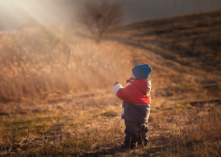 Young happy boy playing outdoor in beautiful rural landscape in golden light at spring. Happy childhood spent in the countryside.の写真素材