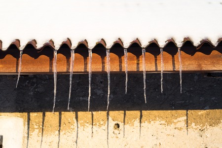 Icicles hanging on roof at winter. Natural ice formation of ice crystals hanging on roof edge at winter.の写真素材