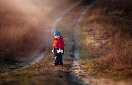 Young happy boy playing outdoor in beautiful rural landscape in golden light at spring. Happy childhood spent in the countryside.の写真素材