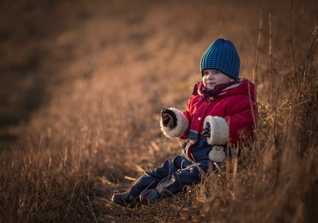Young happy boy playing outdoor in beautiful rural landscape in golden light at spring. Happy childhood spent in the countryside.の写真素材