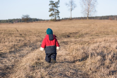 Young happy boy playing outdoor in beautiful rural landscape in golden light at spring. Happy childhood spent in the countryside.の写真素材