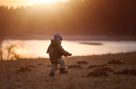 Little boy playing outdoor near forest. Beautiful child photo with golden light.の写真素材