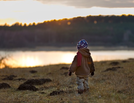 Little boy playing outdoor near forest. Beautiful child photo with golden light.の写真素材