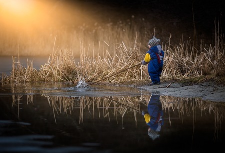 Little boy playing on lake shore. Happy childhood spent in nature.の写真素材