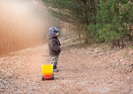 Little boy playing outdoor with a toy car. Beautiful child photo with golden light.の写真素材