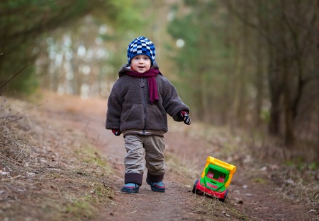 Little boy playing outdoor with a toy car. Beautiful child photo with golden light.の写真素材