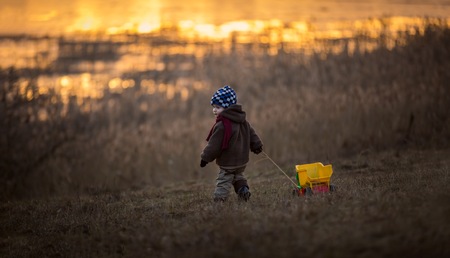 Little boy playing outdoor with a toy car. Beautiful child photo with golden light.の写真素材