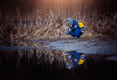 Little boy playing on lake shore. Happy childhood spent in nature.の写真素材