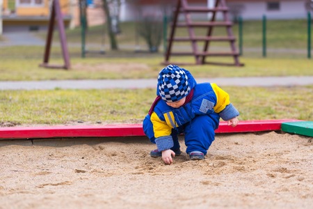 Little boy playing outdoor on city playground at early springtime. Happy 2 years old child.の写真素材