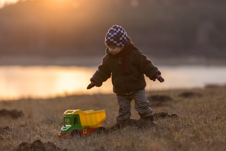 Little boy playing outdoor with a toy car. Beautiful child photo with golden light.の写真素材