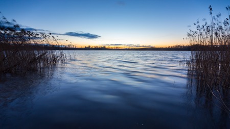 Beautiful sunset over calm lake in Mazury lake district. After sunset sky reflecting in water, calm vibrant landscape.の写真素材