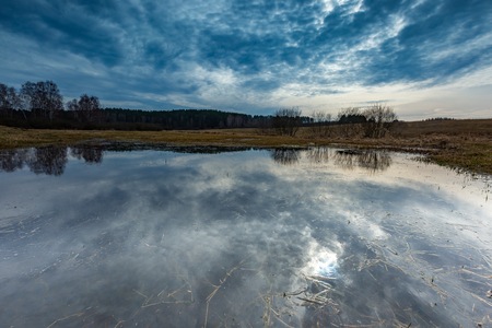 Early springtime on meadow near wetlands. Flooded meadow under cloudy sky. Polish landscapeの写真素材
