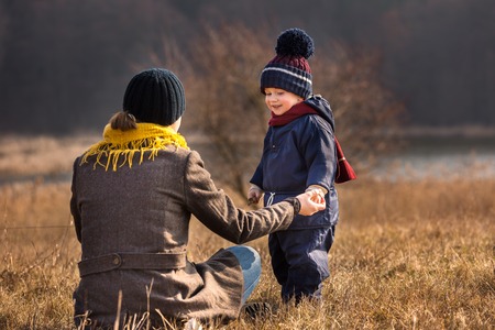 Little boy playing outdoor in spring landscape. Happy caucasian child playing with his motherの写真素材