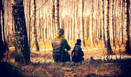 Child and mother sitting on birch tree trunk in forest. Vintage look photoの写真素材