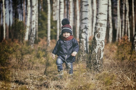 Caucasian boy playing outdoor. Portrait of happy boy playing in springtime forest landscape.