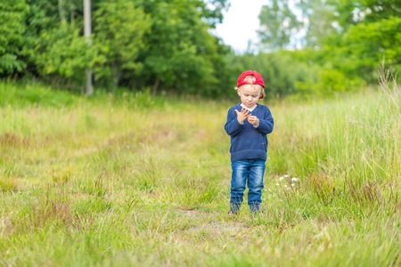 Small caucasian boy playing outdoor on meadow. Little blonde boy in outdoor at spring or summer.の写真素材