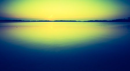 Vintage photo of sunset over calm lake in Poland. Old photo of lake sunset.の写真素材