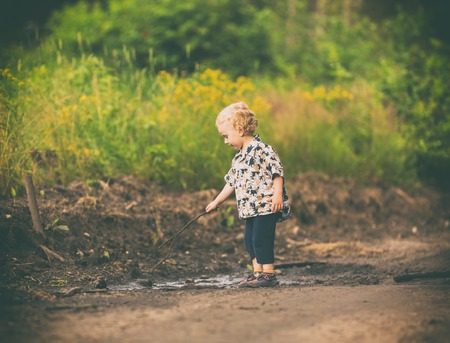 Little boy playing outdoor in summer forest. Polish countryside, photo with vintage mood.の写真素材