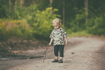 Little boy playing outdoor in summer forest. Polish countryside, photo with vintage mood.の写真素材