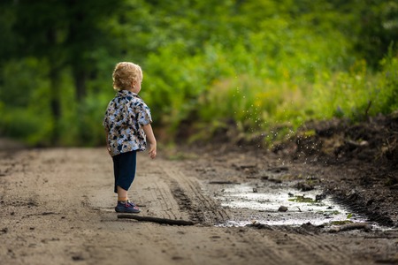 Little boy playing outdoor in summer forest. Polish countryside, photo with vintage mood.の写真素材