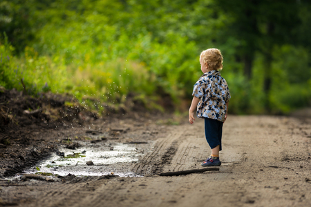Little boy playing outdoor in summer forest. Polish countryside, photo with vintage mood.の写真素材