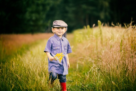 Young boy playing on fields in countryside. Portrait of caucasian happy boy taken in rural polish landscape at evening.の写真素材