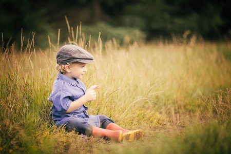 Young boy playing on fields in countryside. Portrait of caucasian happy boy taken in rural polish landscape at evening.の写真素材