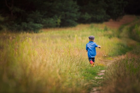 Young boy playing on fields in countryside. Portrait of caucasian happy boy taken in rural polish landscape at evening.の写真素材