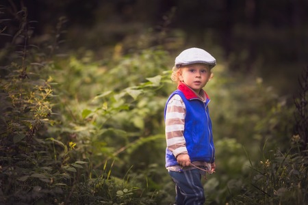 Little boy playing in nature. Caucasian boy and green landscape.