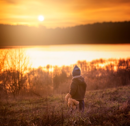 Boy playing outdoor in autumn or spring scenery. Caucasian boy in hat in sunset light in autumnの写真素材