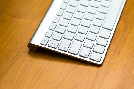 Close up of white wireless aluminum keyboard photographed with shallow depth of field.
