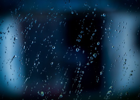Water droplets on window at dark autumnal rainy day.の写真素材