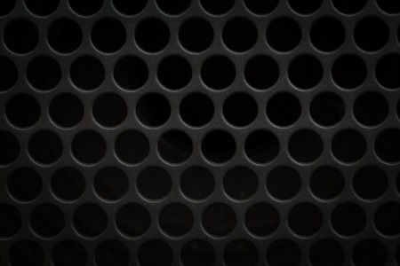 Dark grid background. Close up of aluminum speaker. Texture with holes.の写真素材