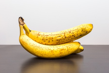 Bunch of bananas lying on dark wooden table. Bananas in close up.の写真素材