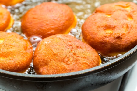 Donuts frying in deep fat. Preparation of traditional donuts