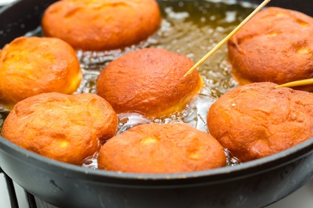 Donuts frying in deep fat. Preparation of traditional donutsの写真素材