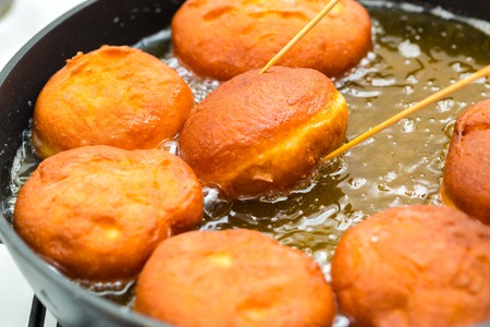 Donuts frying in deep fat. Preparation of traditional donutsの写真素材