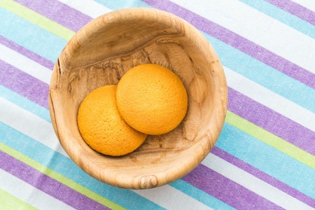 Biscuits cakes in wooden bowl on table. Close up of spongecakes.